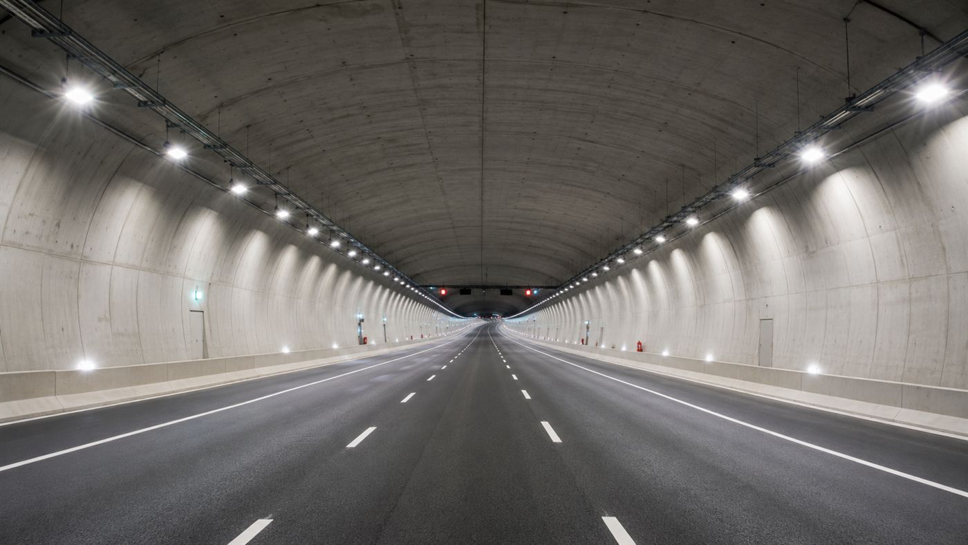 The brightly lit interior of an undersea tunnel showing a multi-lane motorway alongside a separate railway tube