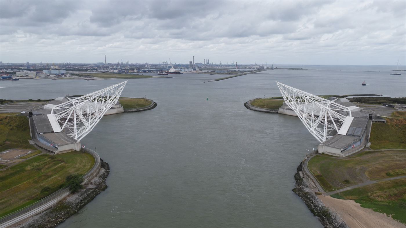 Aerial view of the two huge white steel arms of the Maeslant storm surge barrier on the banks of a canal near Rotterdam