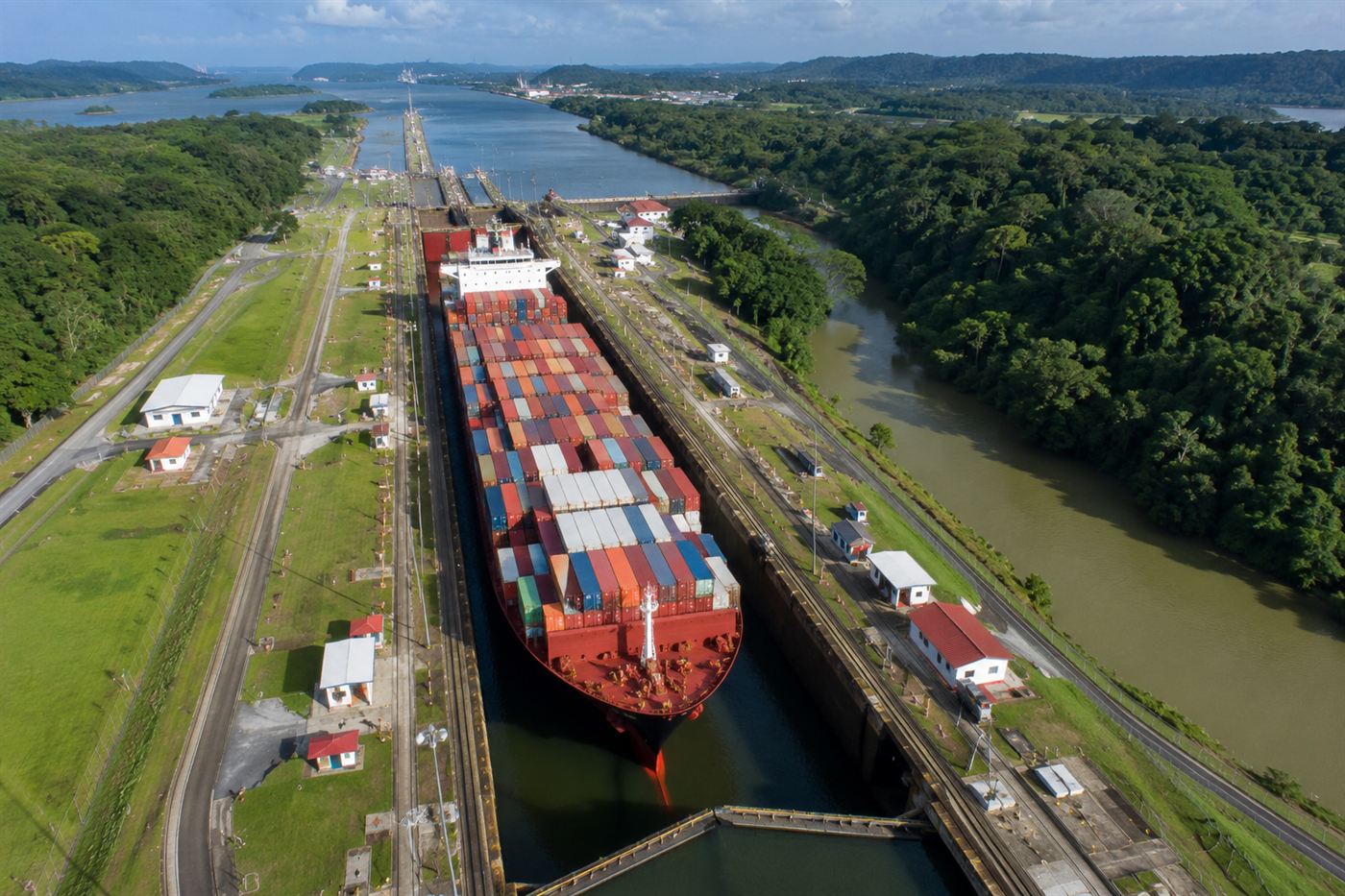 A huge container ship squeezed into a narrow Panama Canal lock surrounded by tropical forest