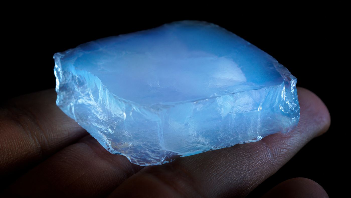 A translucent bluish block of aerogel glowing like solid frozen smoke against a dark background