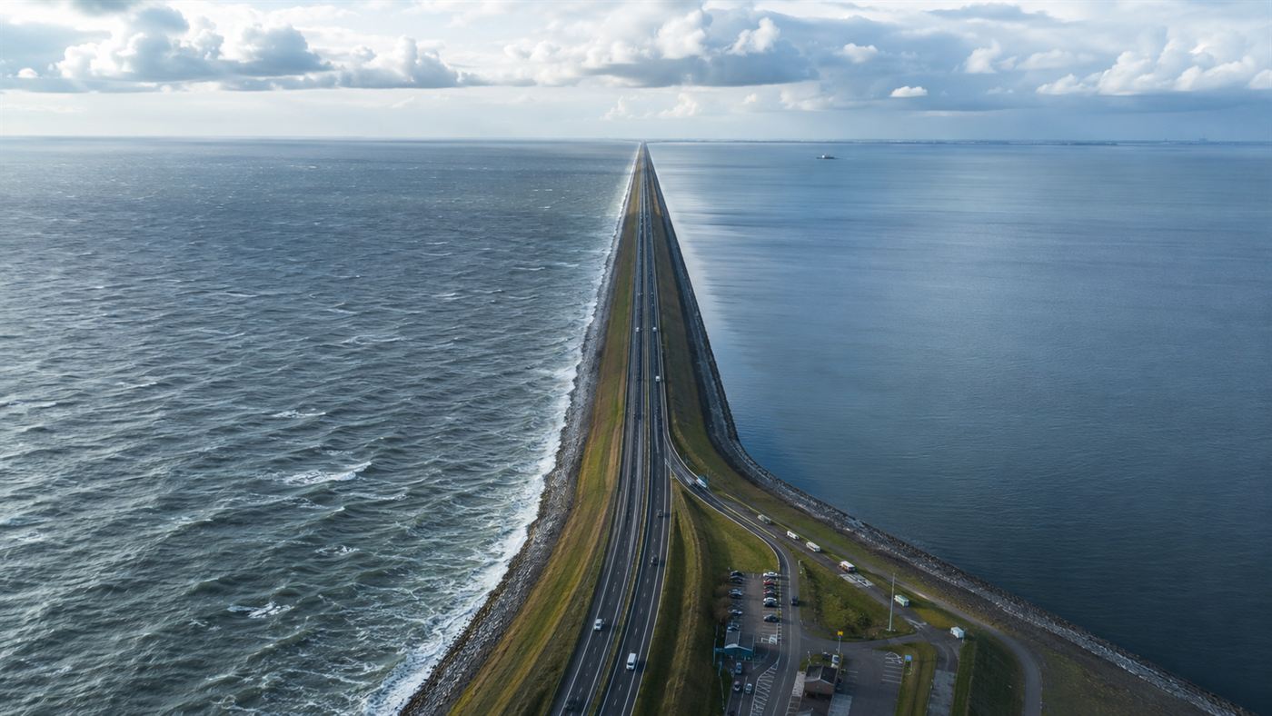 The long straight Afsluitdijk dam stretching to the horizon with the sea on one side and a calm lake on the other