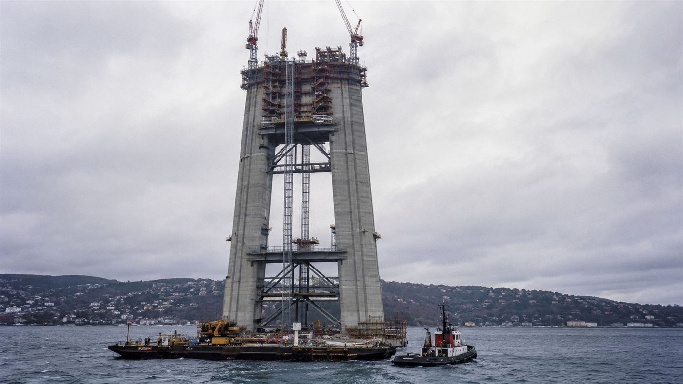 One of the Akashi Kaikyo Bridge's huge towers under construction over the strait with cranes