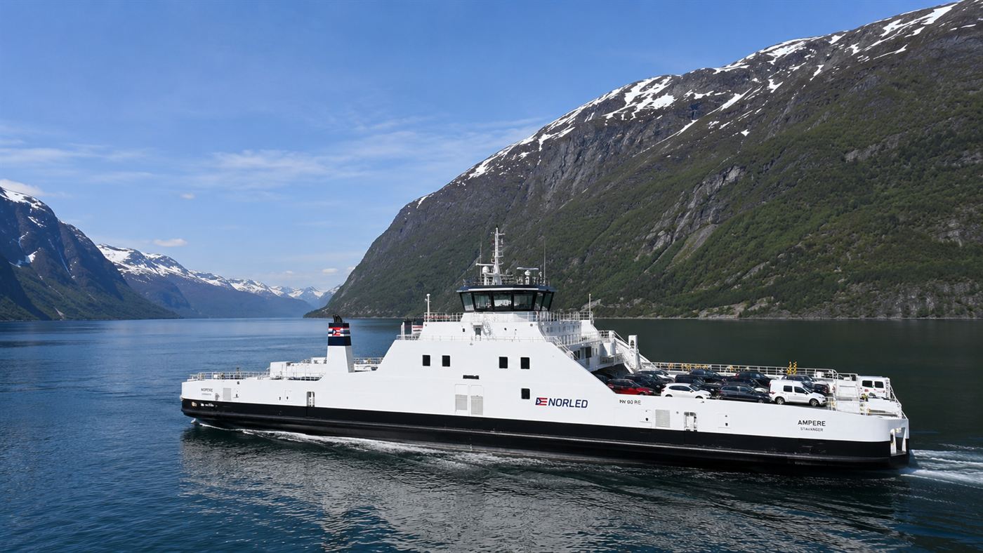 The white electric car ferry Ampere crossing a calm Norwegian fjord with steep green mountains rising on either side
