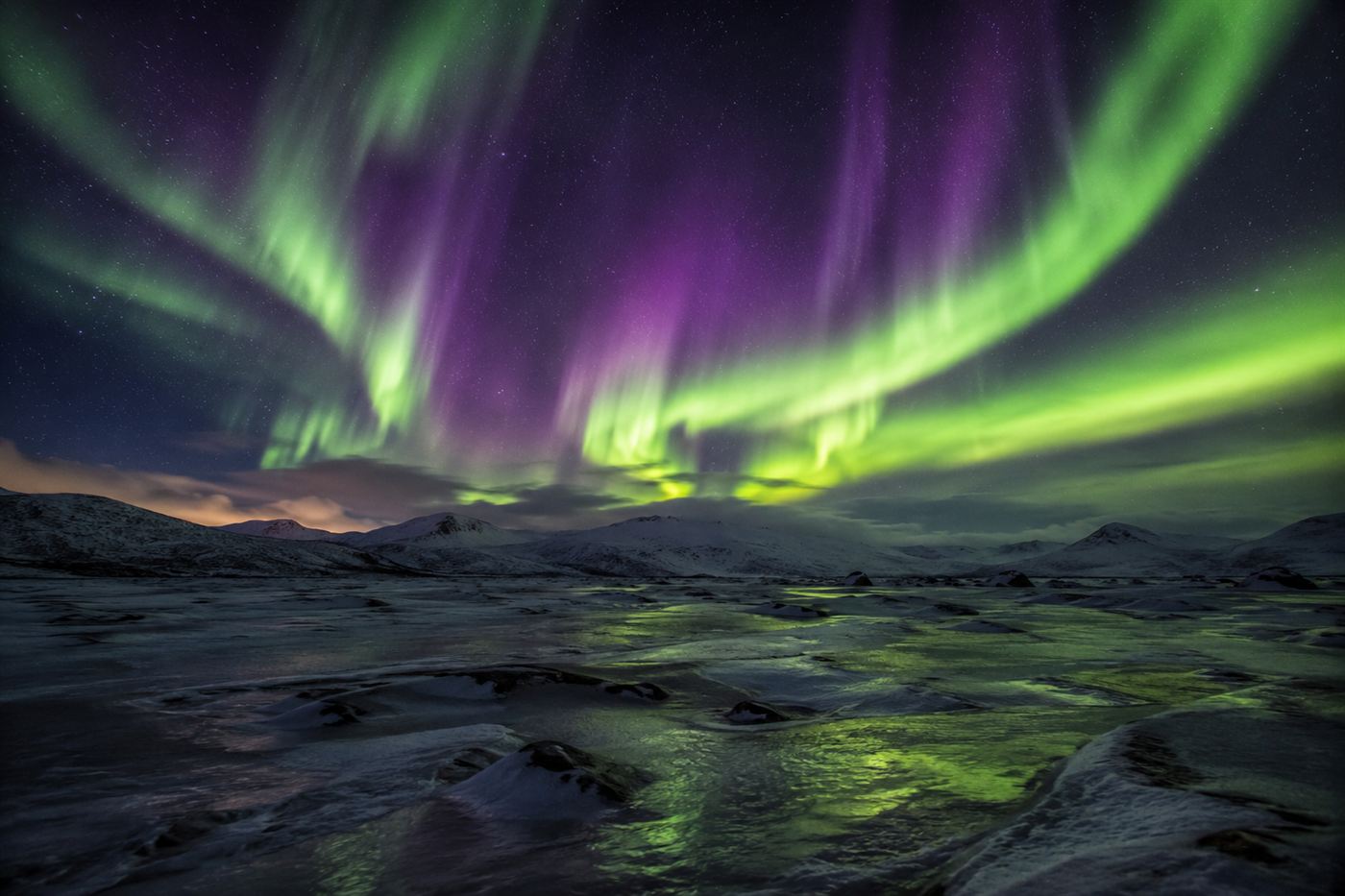 Aurora over a frozen Arctic landscape, the visible glow of the magnetic field linked to the magnetic north pole