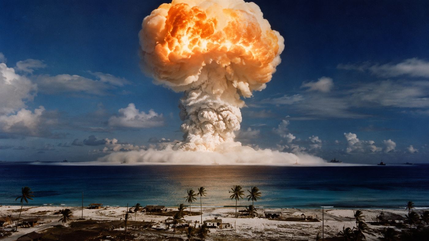 The Castle Bravo hydrogen bomb mushroom cloud rising over Bikini Atoll in the Marshall Islands on March 1 1954, an enormous orange and white fireball expanding above the Pacific with the shock wave spreading across the sea below