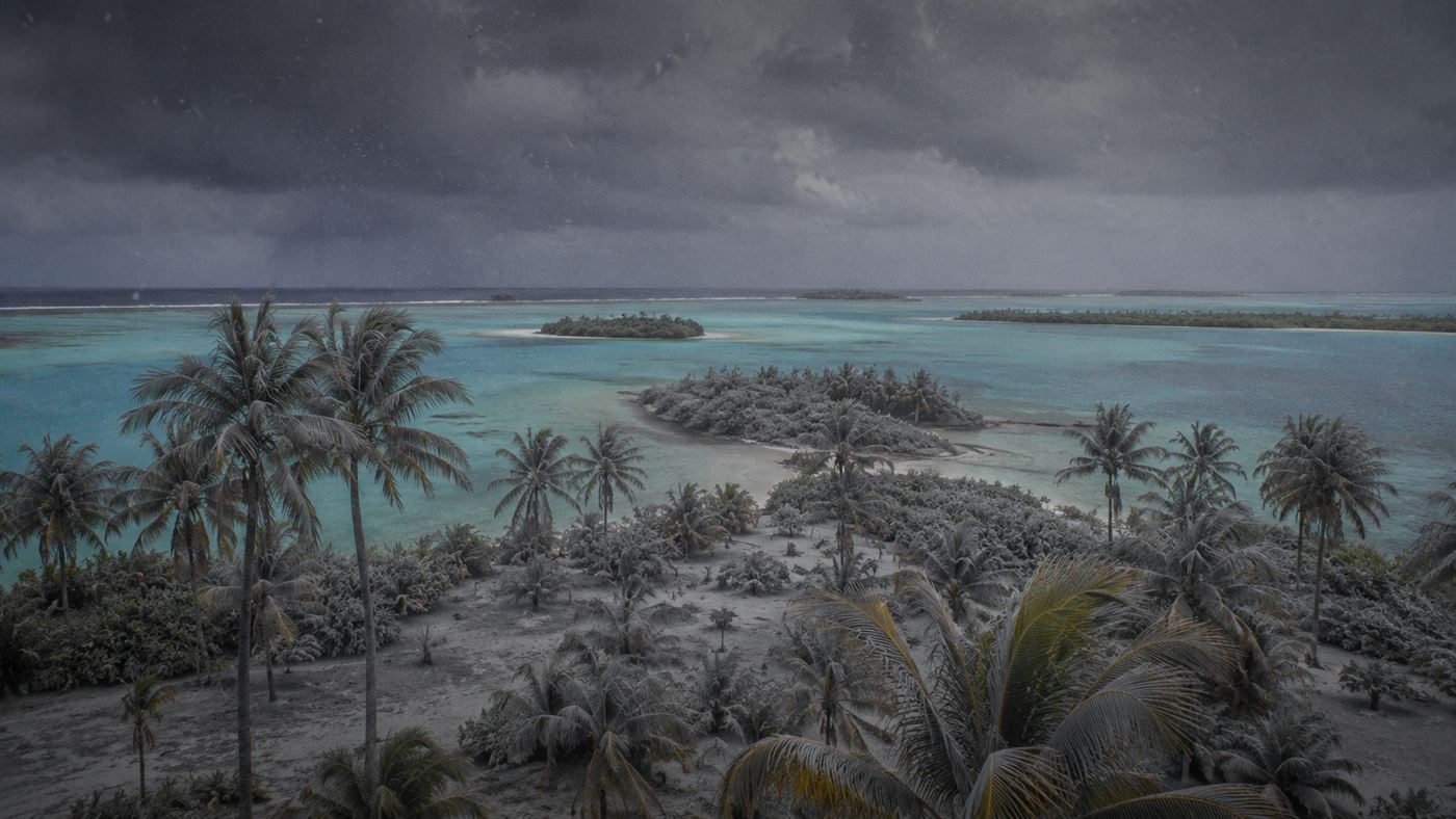 Grey ash-like nuclear fallout drifting down over a remote tropical coral atoll with palm trees under a darkening sky