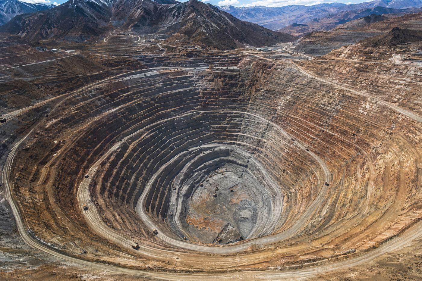 An aerial view of the vast terraced spiral of the Bingham Canyon open-pit copper mine, a kilometre deep, under a clear sky