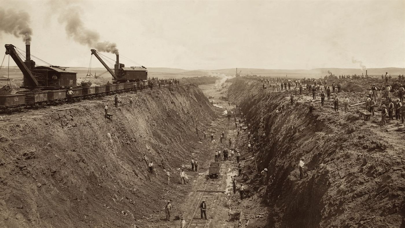 A vast canal excavation around 1900 with early steam shovels and hundreds of laborers digging a deep trench, part of the Sanitary and Ship Canal