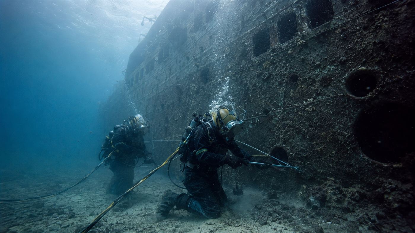Commercial divers working underwater on the maritime salvage of a large capsized cruise ship hull