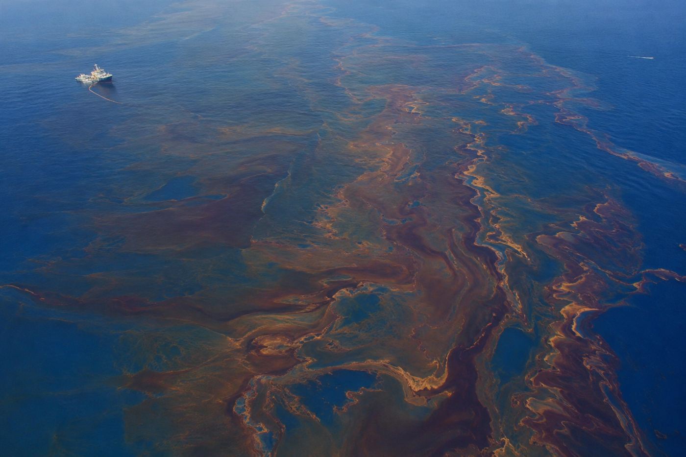 Aerial view of the BP Macondo oil spill spreading across the Gulf of Mexico surface in May 2010, dark oil sheen visible against the blue water