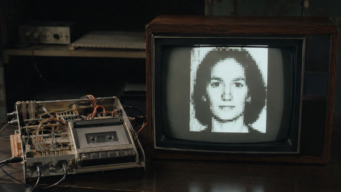 A blocky black-and-white digital image displayed on a 1970s cathode-ray television connected to the prototype camera