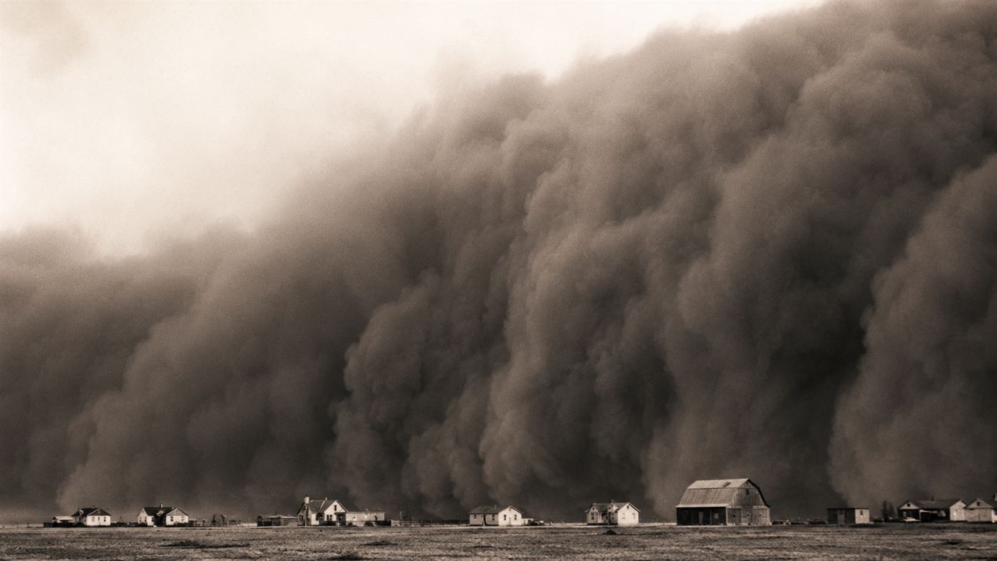 A towering black wall of dust from the 1935 Dust Bowl storm rolling over a small Great Plains farm town