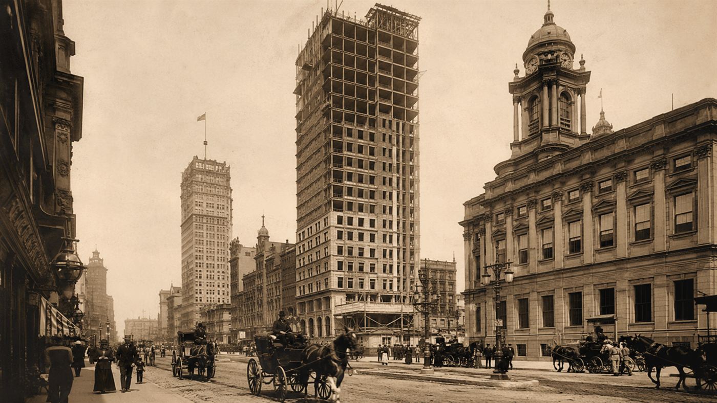 Early steel-framed skyscrapers rising over a late-19th-century American city street, made possible by passenger elevators