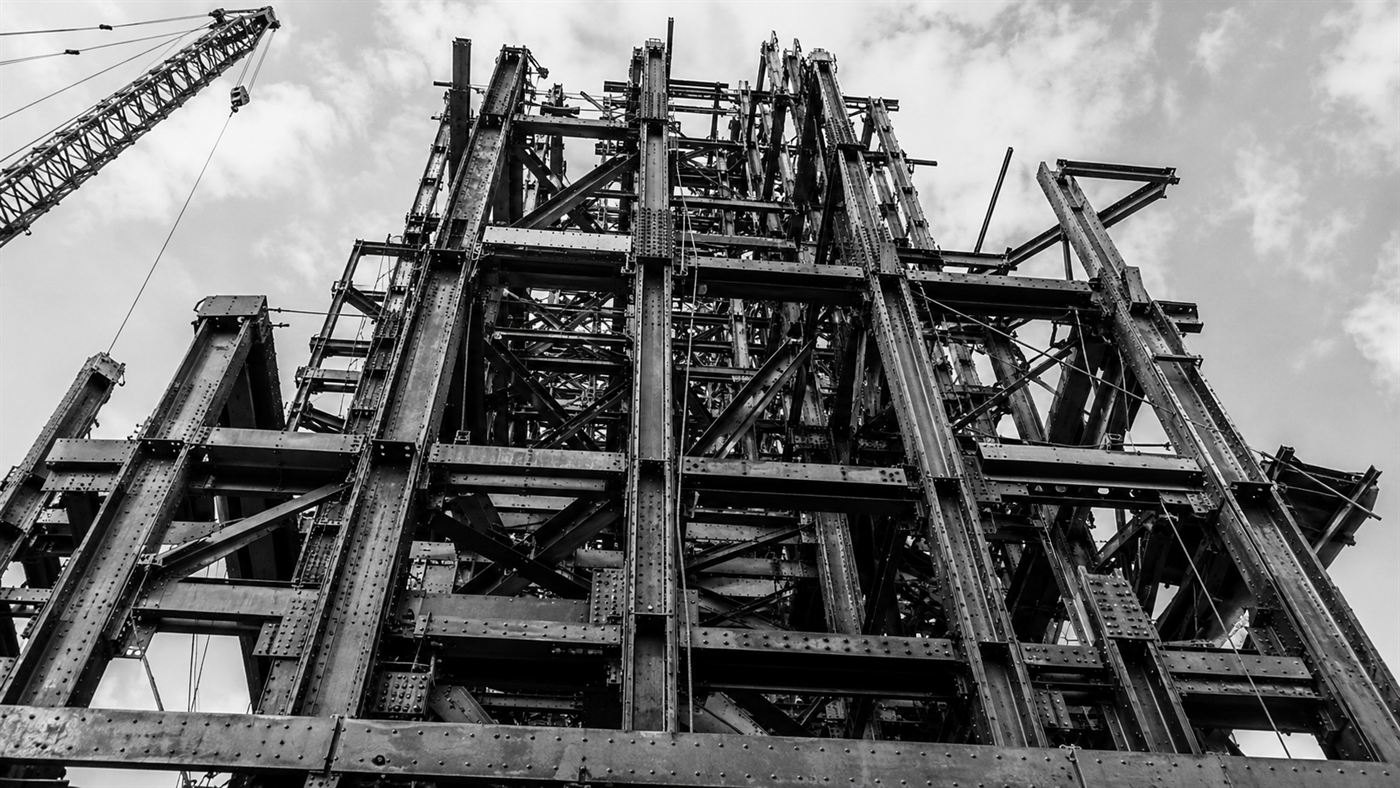 The riveted steel skeleton of a 1930s skyscraper under construction, showing the dense frame that absorbed the 1945 impact
