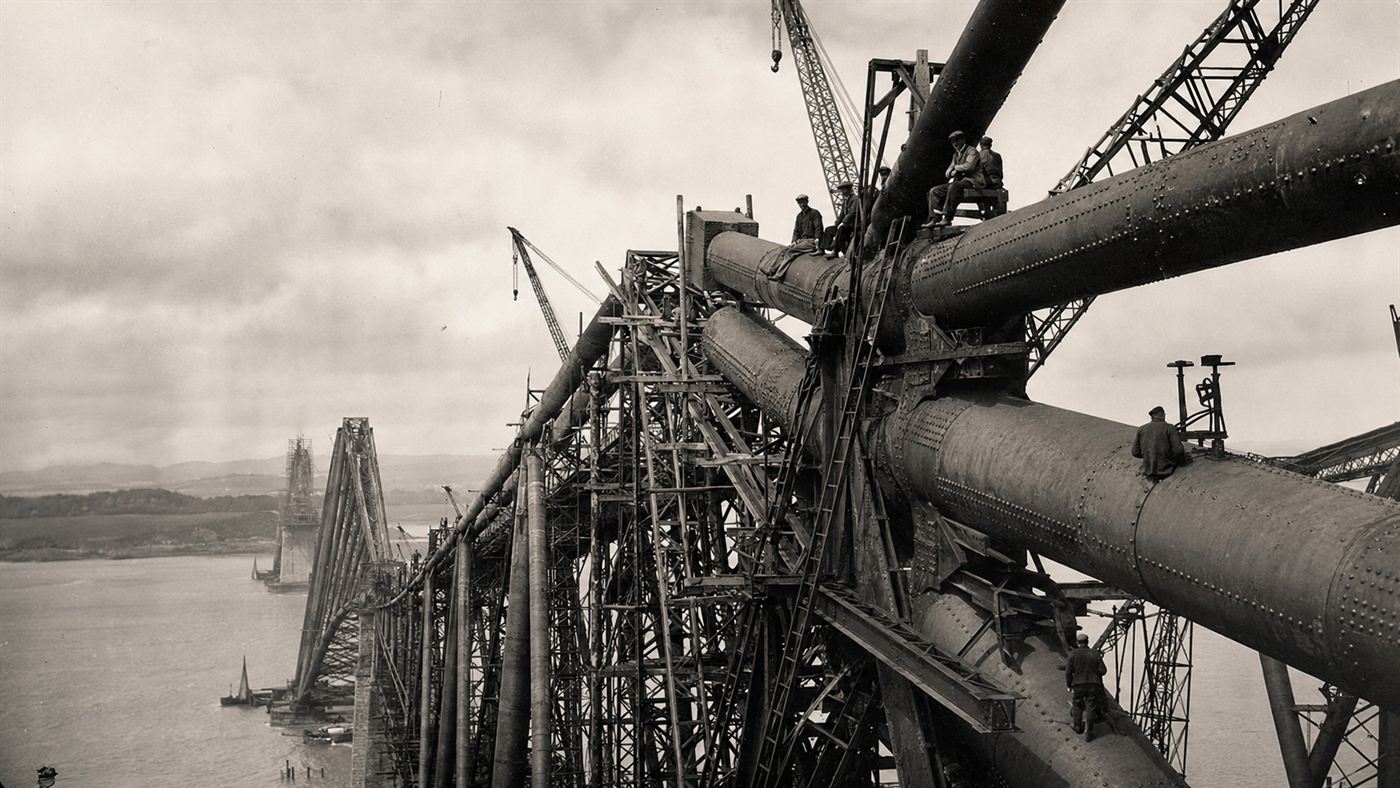 Workers high on the half-built steel cantilever Forth Bridge over the estuary in the 1880s