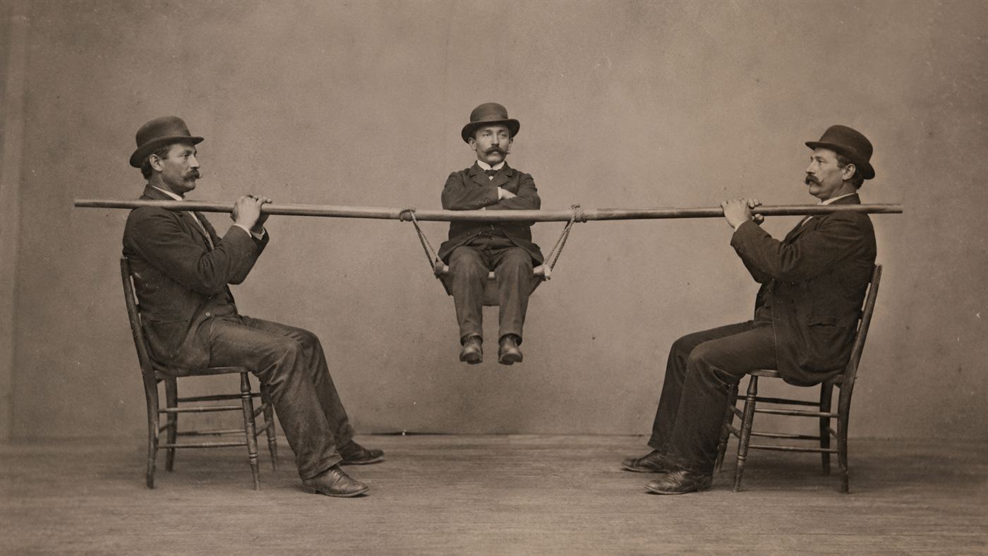 Two seated men with arms in tension holding up a third man between them, the human cantilever demonstration for the Forth Bridge
