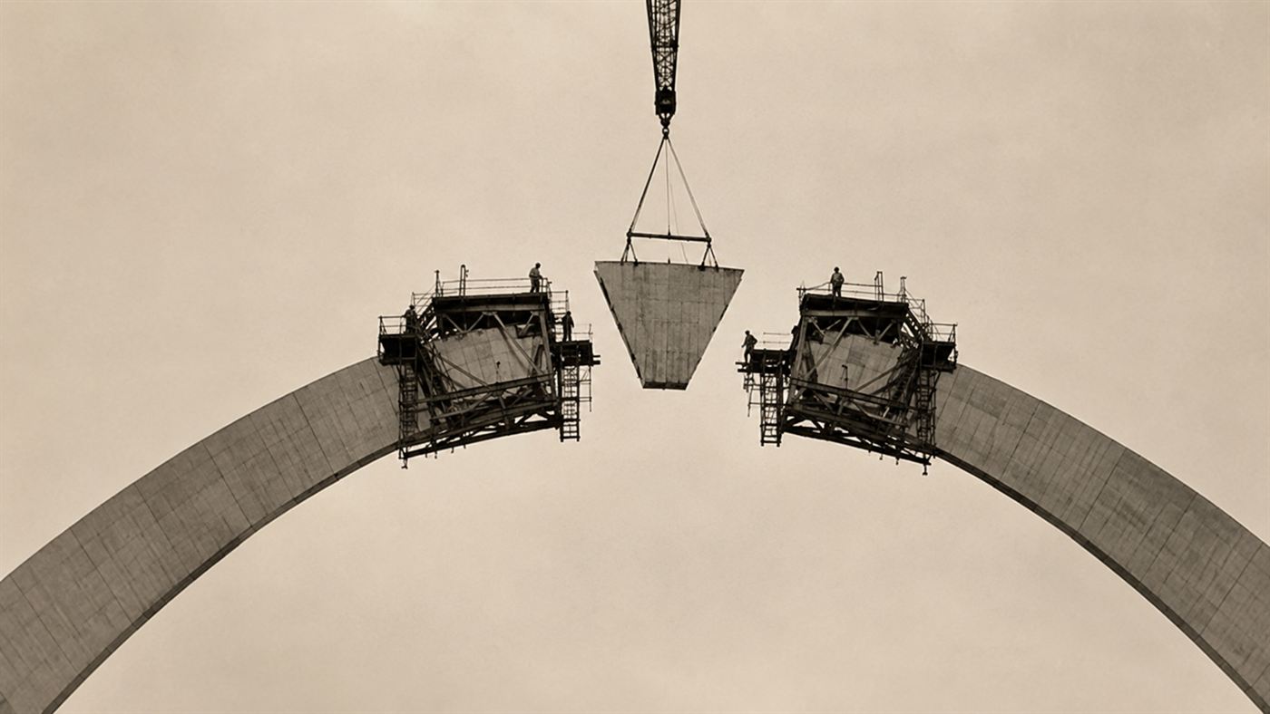 Workers and hydraulic jacks fitting the final triangular keystone section at the top of the Gateway Arch in 1965