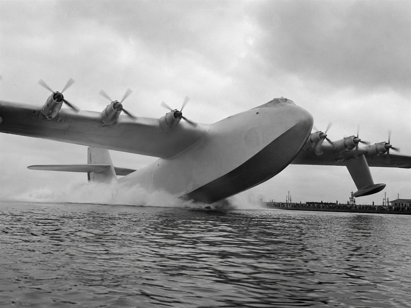 The Spruce Goose H-4 Hercules flying boat lifting off from Long Beach harbor on November 2, 1947, the wooden eight-engine WWII aircraft rising above the water during its only flight, Howard Hughes at the controls