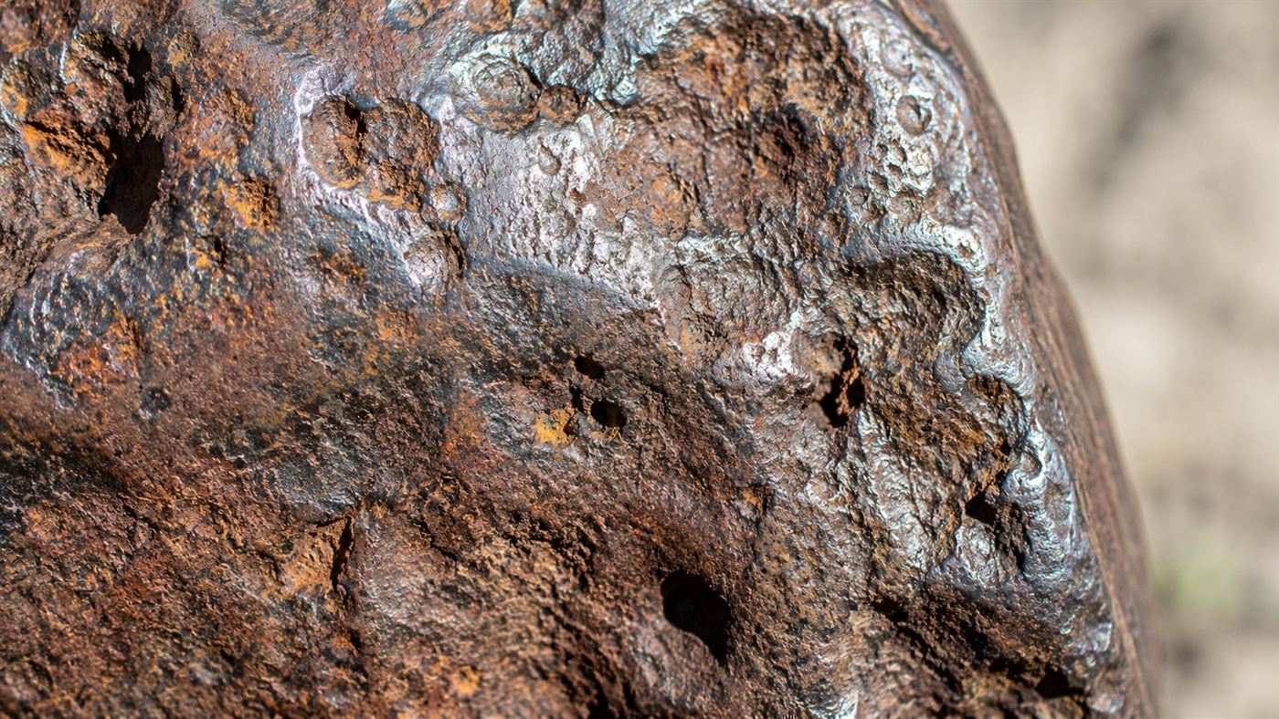 A close-up of the pitted, rusted iron-nickel surface of the Hoba meteorite