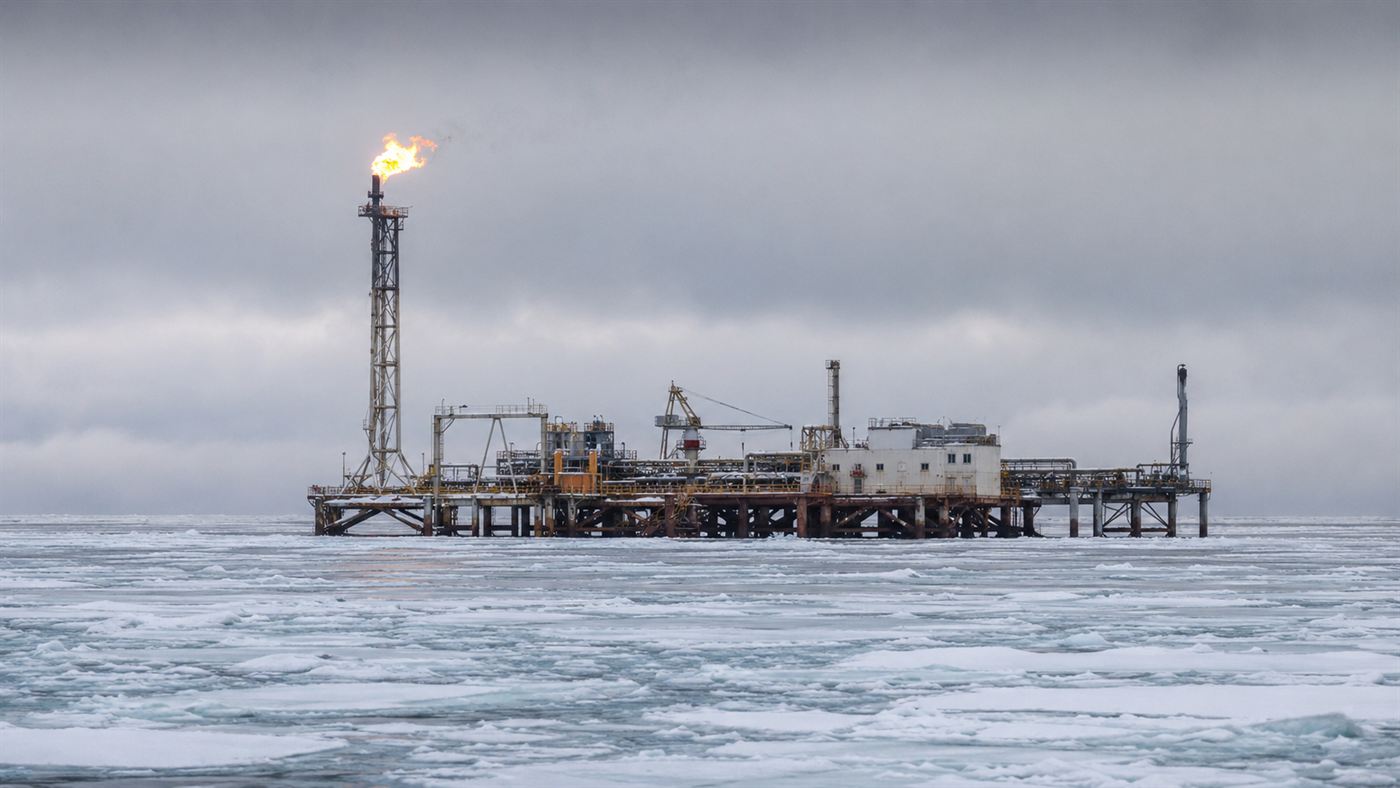 A Kashagan oil field production island of steel rising from a frozen Caspian Sea with a gas flare burning against a grey winter sky