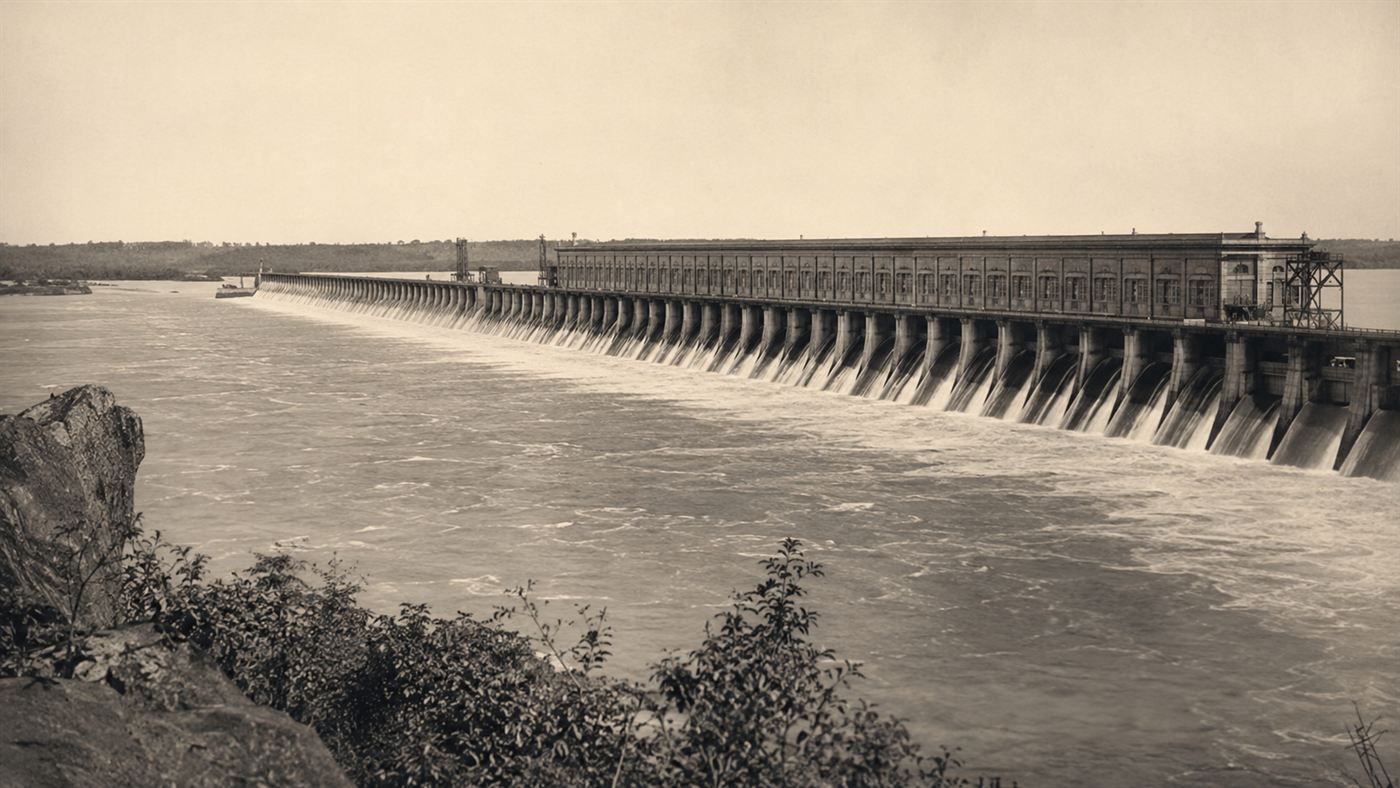 The long Keokuk Dam and powerhouse stretching across the wide Mississippi River in 1913, water spilling over its gates
