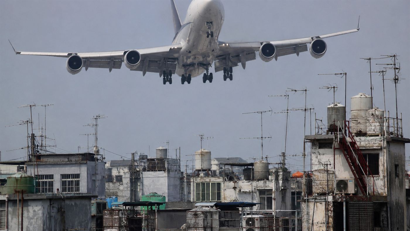 A passenger jet flying very low over the crowded antenna-covered rooftops near Kai Tak, the height limit on the Kowloon Walled City