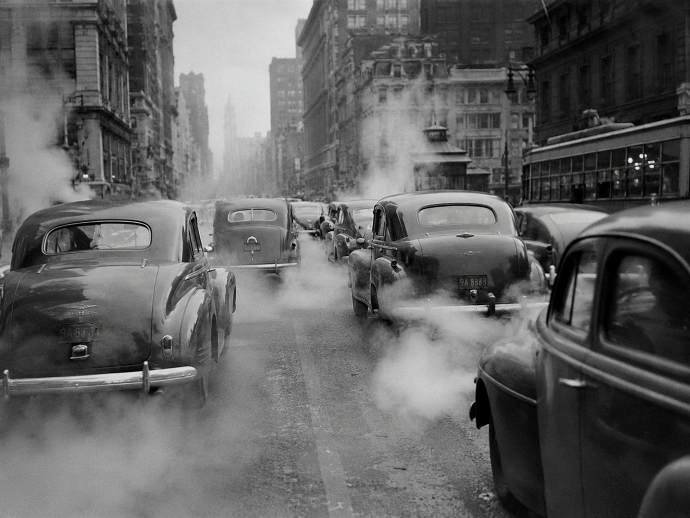 Leaded gasoline exhaust from vintage cars on 1940s American city street, lead poisoning contaminating urban air for decades through automotive emissions