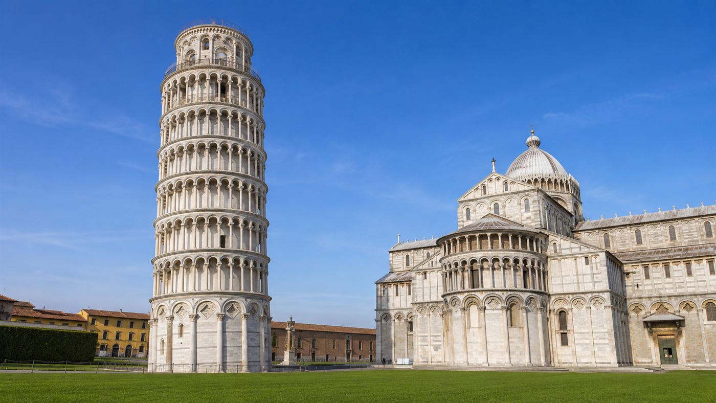 The Leaning Tower of Pisa tilting against a blue sky, the white marble bell tower in its grassy square