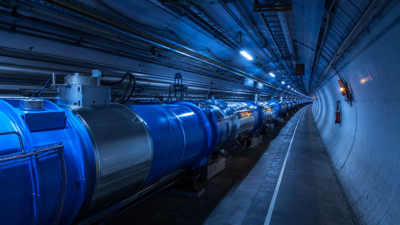 The blue tunnel of the Large Hadron Collider curving away into the distance, lined with its huge cylindrical magnets