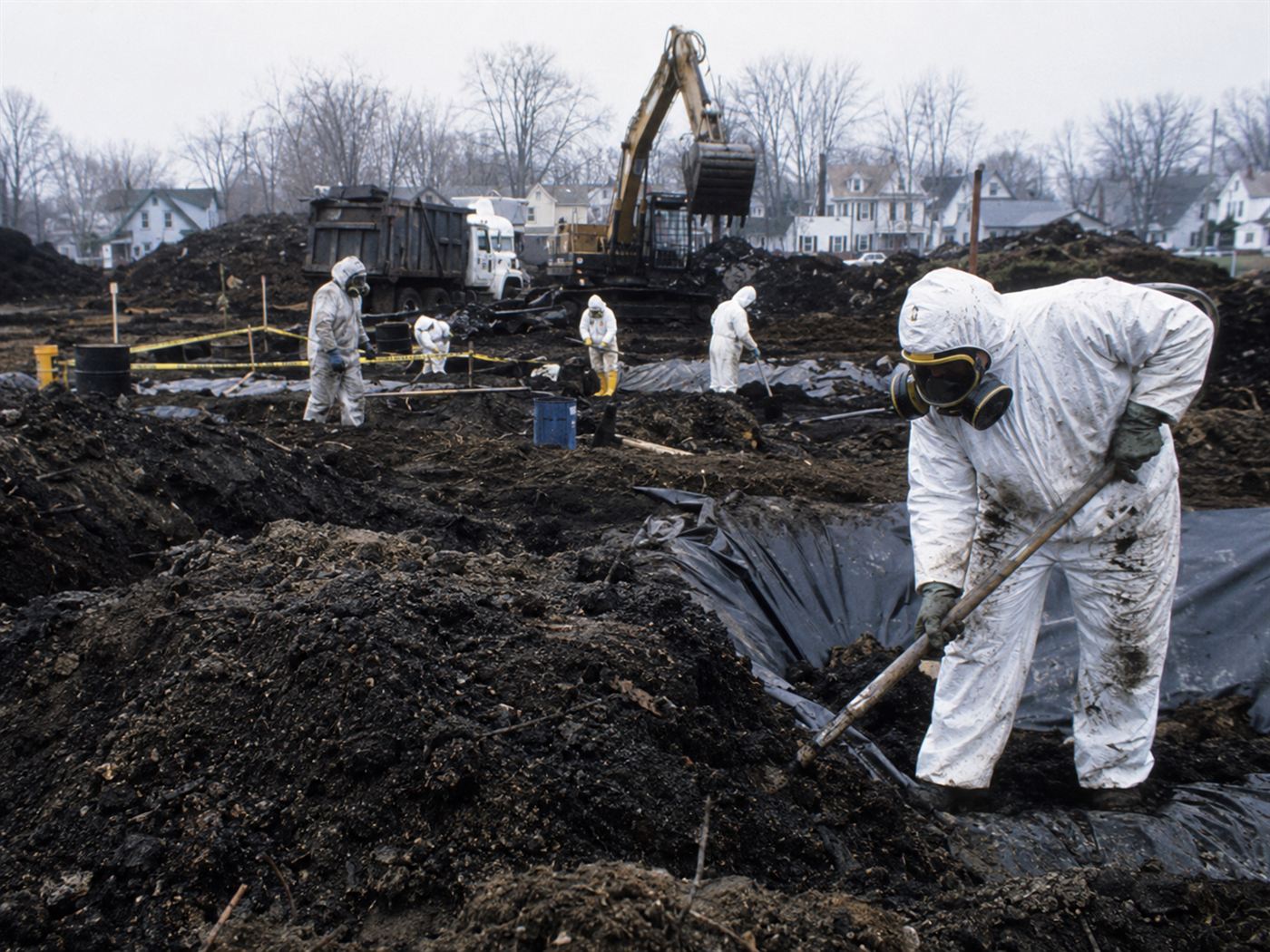 Love Canal toxic waste remediation site Niagara Falls New York, hazmat workers in protective suits excavating contaminated soil, waste barrels being removed from Love Canal cleanup