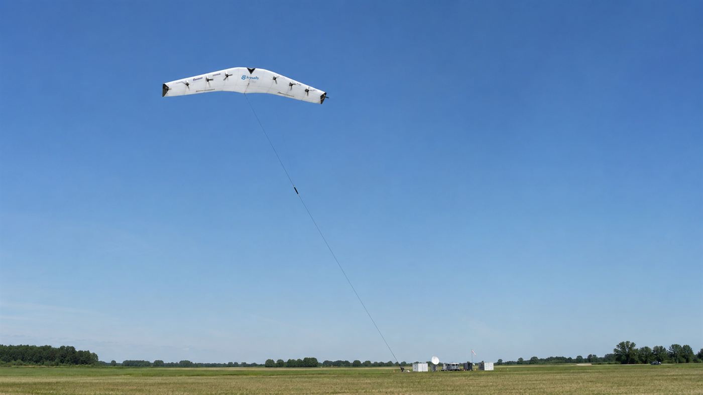 A rigid winged Makani energy kite with rotors flying high in the sky on a long tether