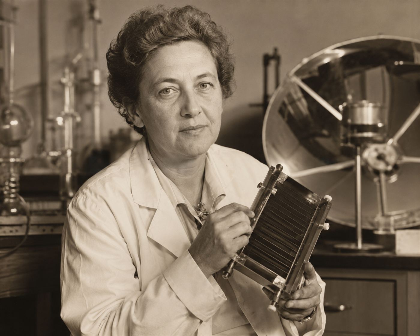 A 1950s portrait of scientist Maria Telkes in a laboratory holding solar apparatus