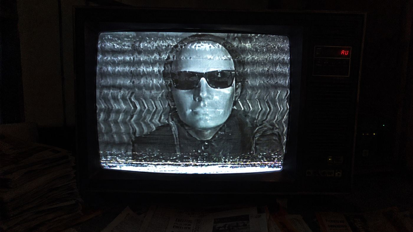A 1980s television showing a glitchy masked figure against a wavy background, evoking the Max Headroom hijack