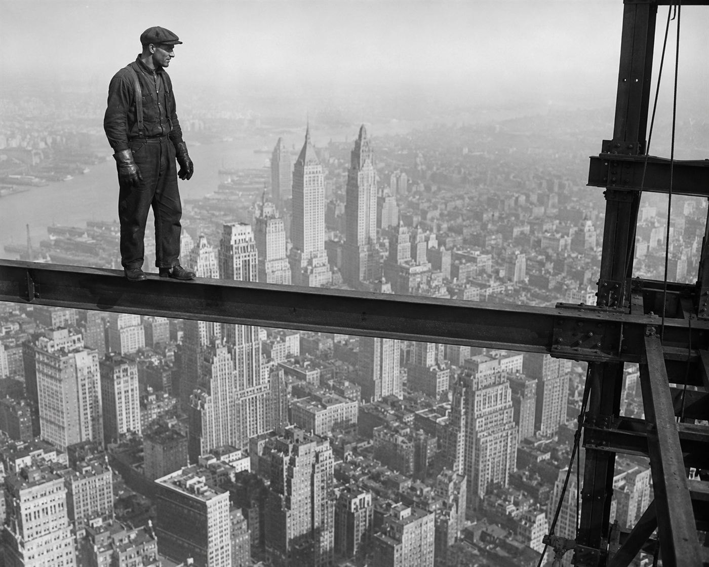 An ironworker balanced on a steel beam high above the New York City skyline