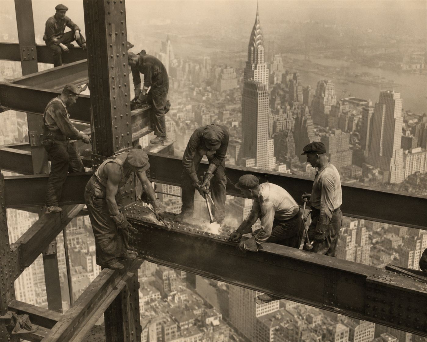 A riveting gang of ironworkers fastening rivets on the steel frame of a skyscraper high above 1930s New York