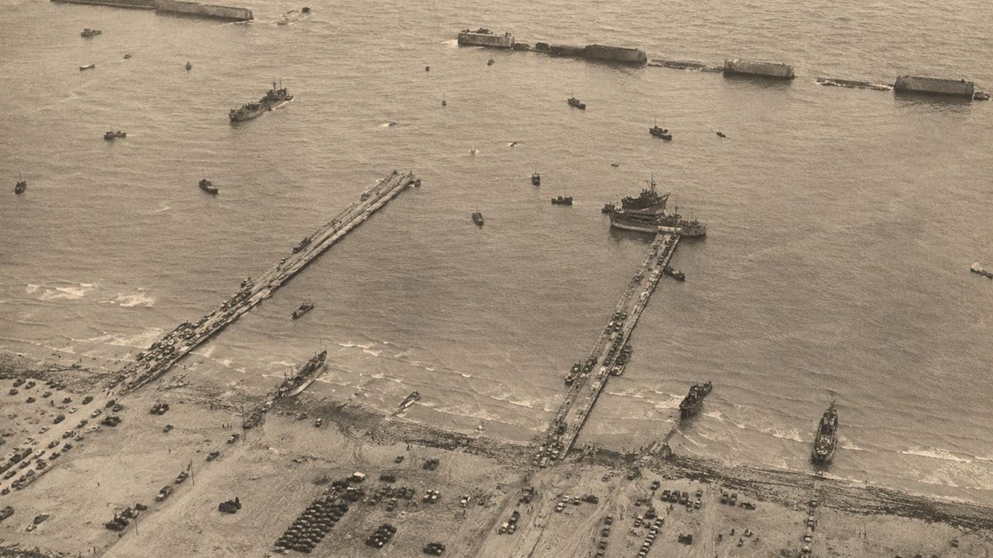 A World War Two Mulberry harbour off the Normandy coast with floating roadways, concrete breakwaters and ships unloading