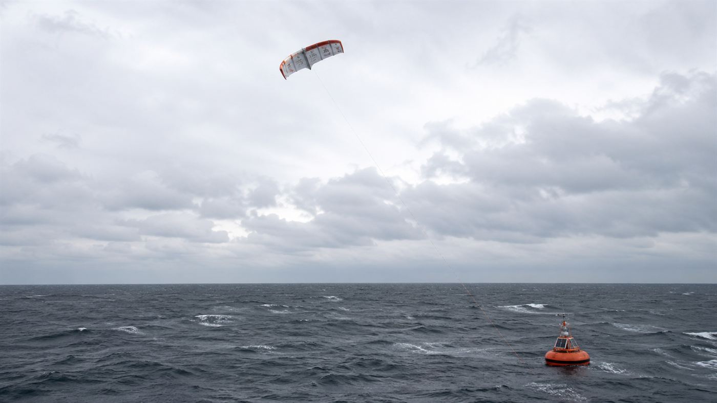 An energy kite flying above a small anchored buoy on the open grey North Sea, far from land