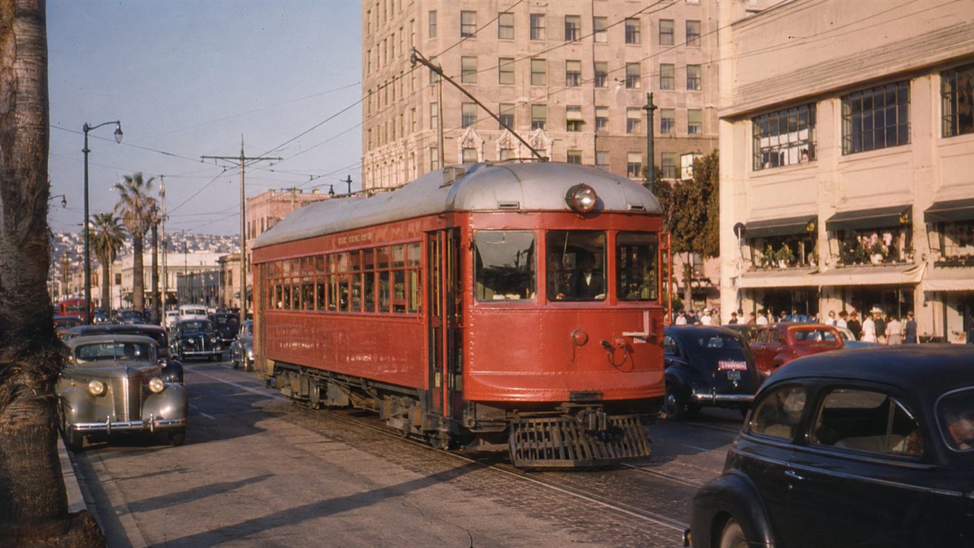 A Pacific Electric Red Car streetcar running through 1940s Los Angeles traffic