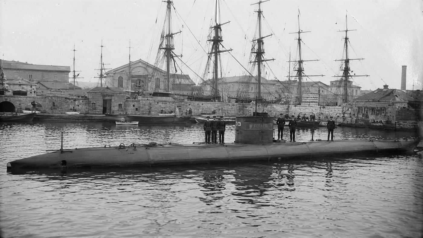 The cigar-shaped Peral submarine of 1888 floating at a Spanish naval arsenal with sailors on its deck