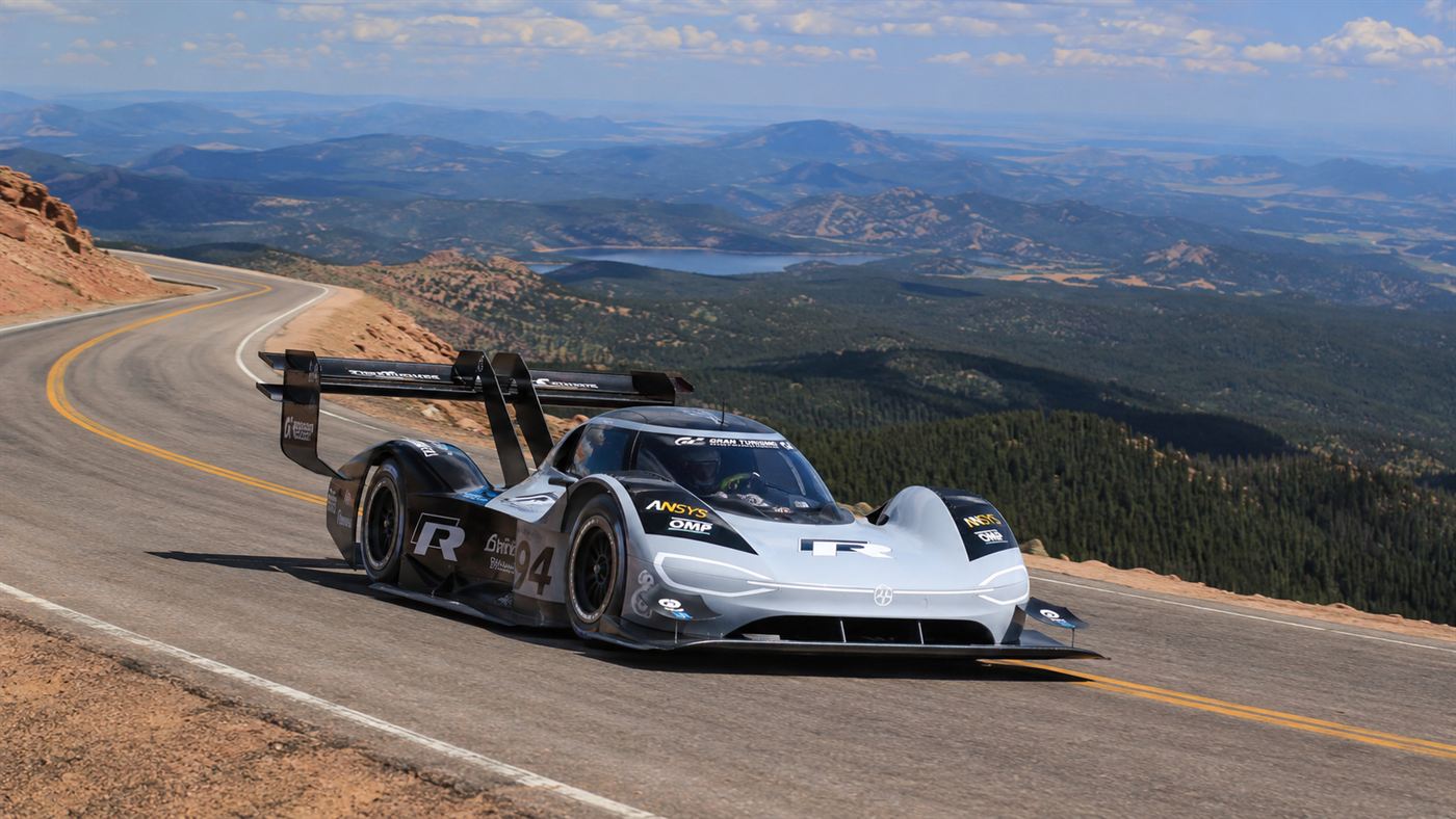 The black and white electric Volkswagen ID.R race car with a huge rear wing climbing a mountain road on Pikes Peak