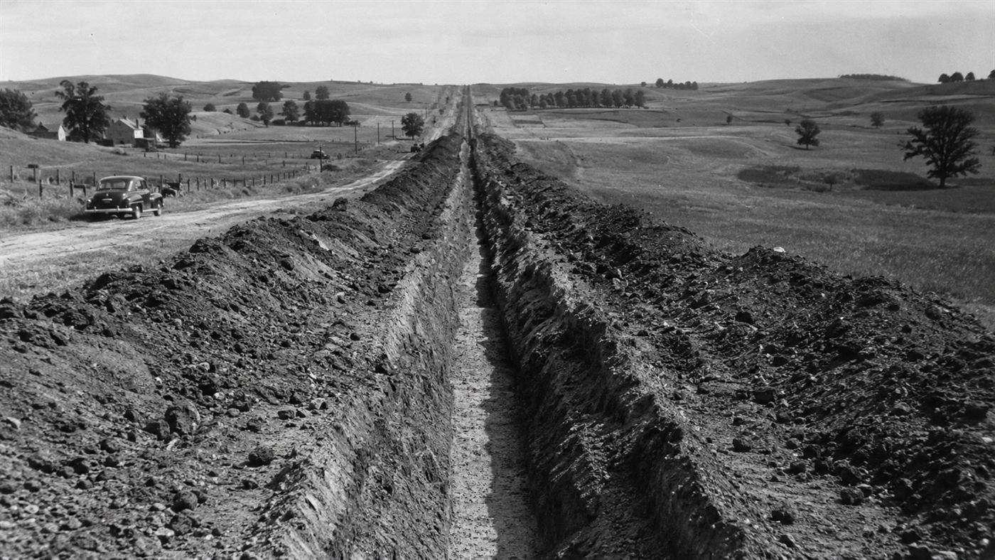 A long open trench for the Big Inch pipeline cutting straight across the American countryside in the 1940s