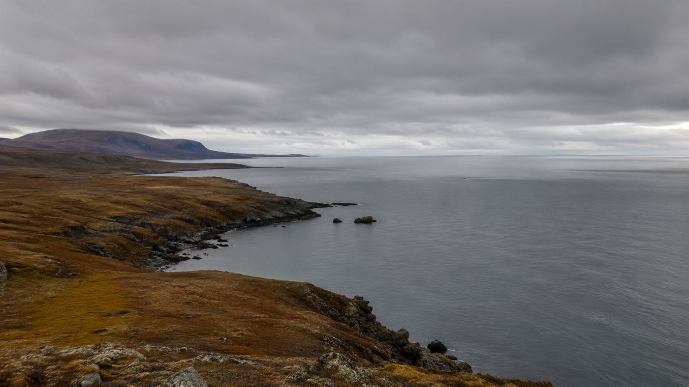 A remote, rugged Alaskan coastline of tundra and cold sea, the proposed site for a nuclear-blasted harbor