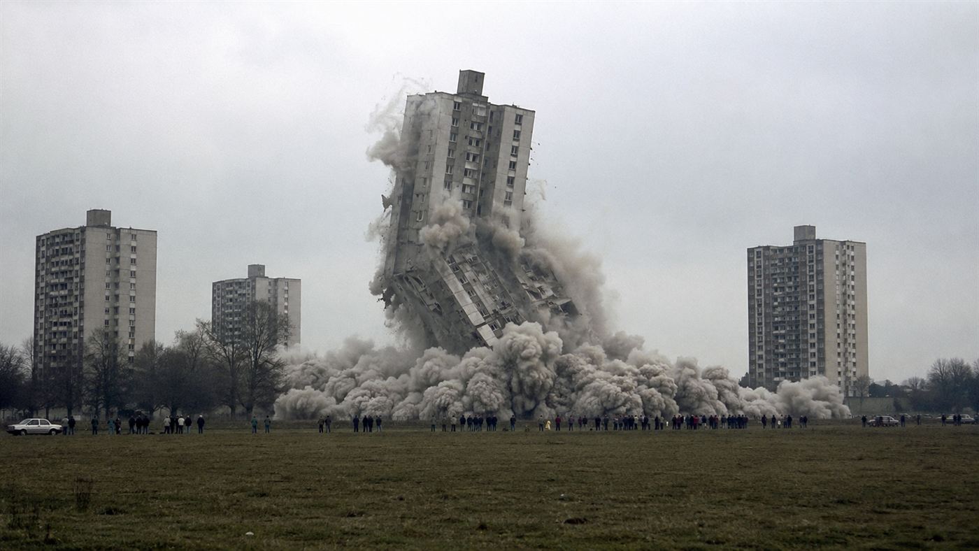 The 1972 controlled demolition of a tall Pruitt-Igoe concrete apartment tower collapsing into a huge cloud of dust seen across a field