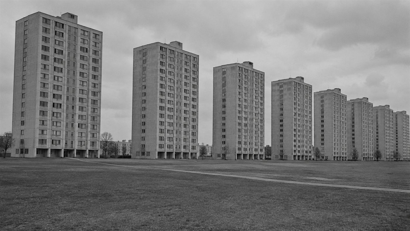 A row of identical austere 11-storey modernist concrete Pruitt-Igoe apartment towers under a grey sky in 1950s St Louis