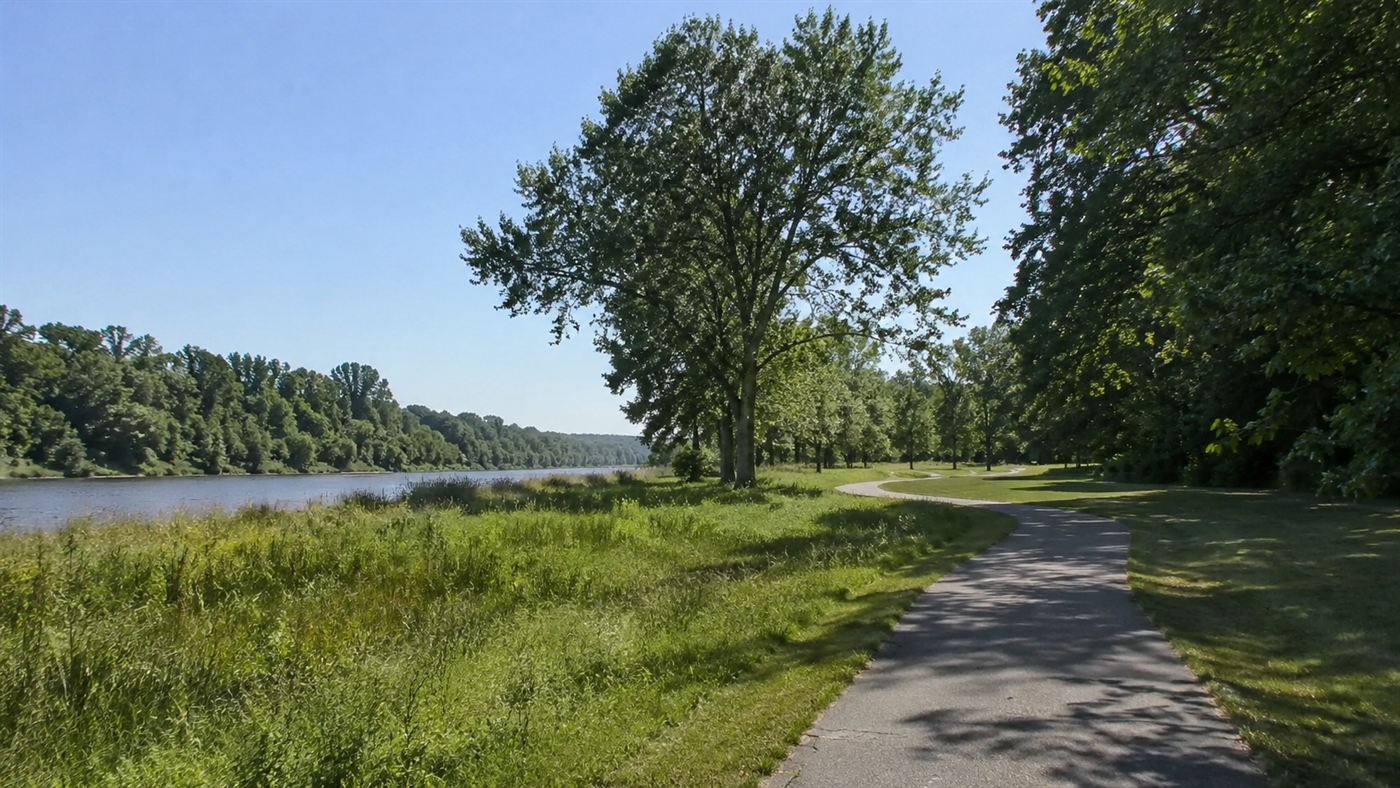 A green riverside state park with walking trails and trees on the site of a former town