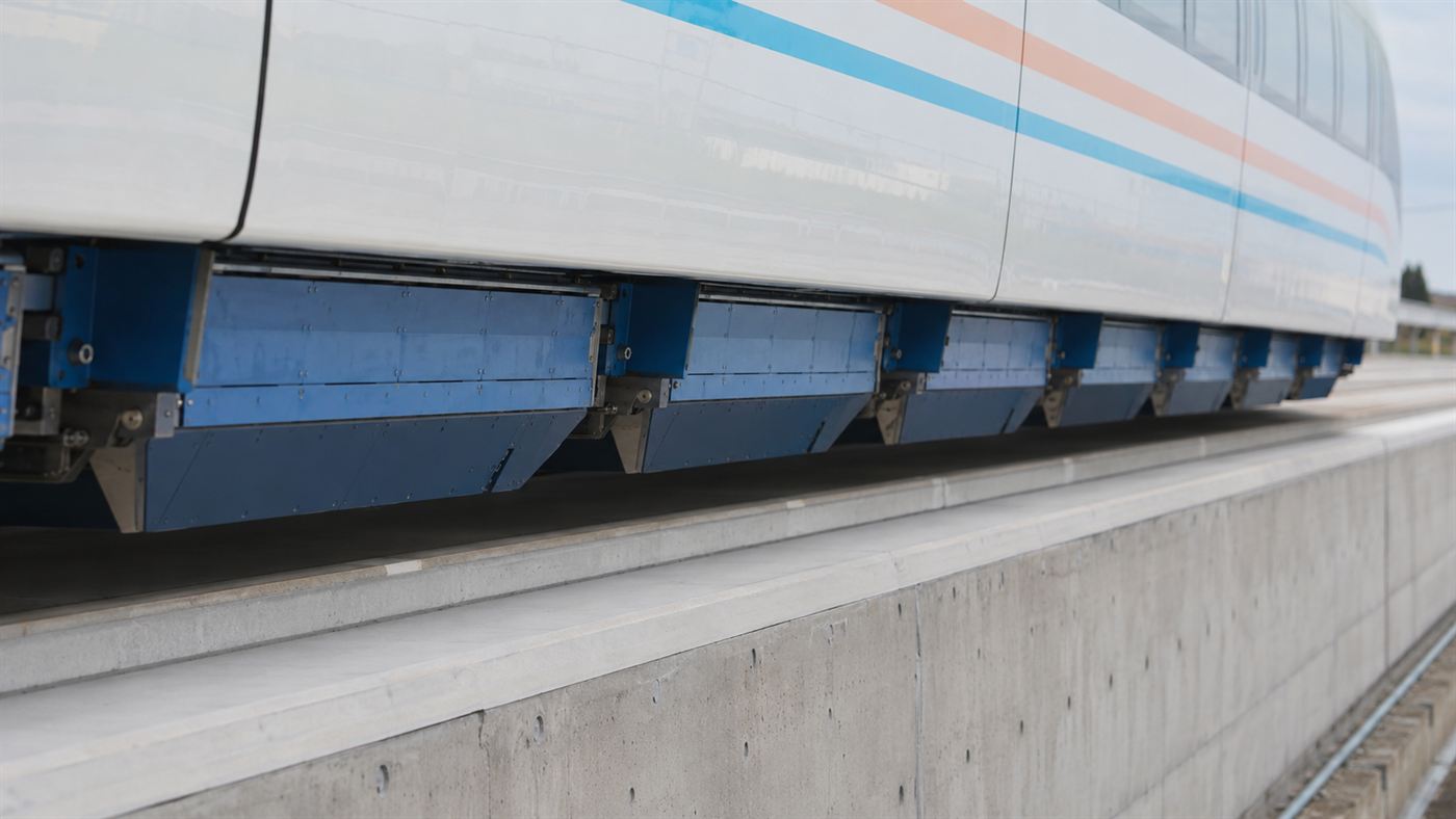 A close-up of an SCMaglev carriage hovering above its concrete guideway with a visible gap and blue magnet housings