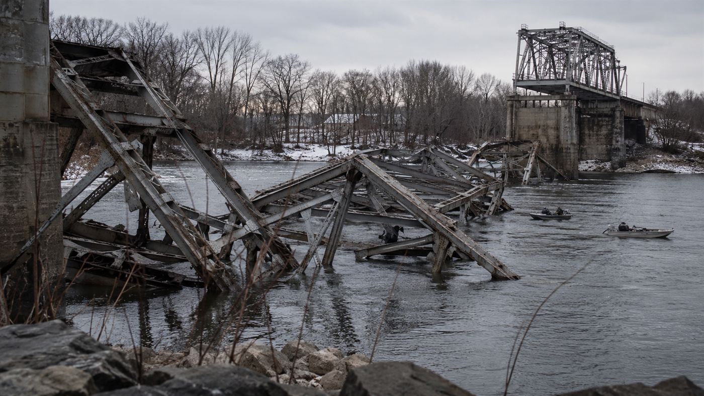 Twisted steel wreckage of the collapsed Silver Bridge lying in the cold grey Ohio River with rescue boats under a bleak sky