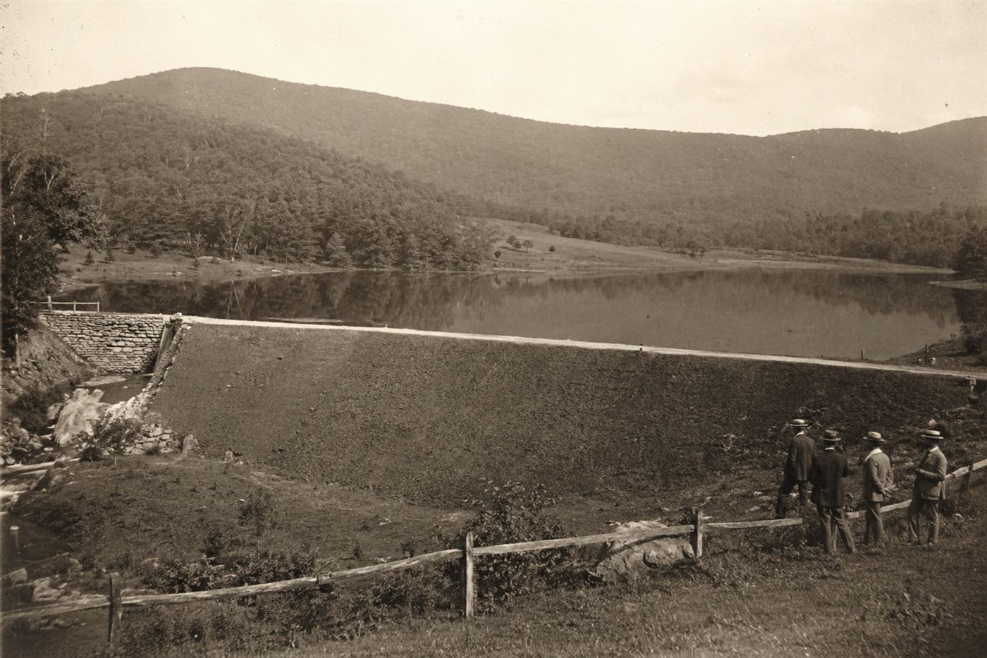 The South Fork earthen dam in rural Pennsylvania mountains held back a large reservoir lake used as private fishing retreat by wealthy Gilded Age industrialists in the 1880s before the dam failure