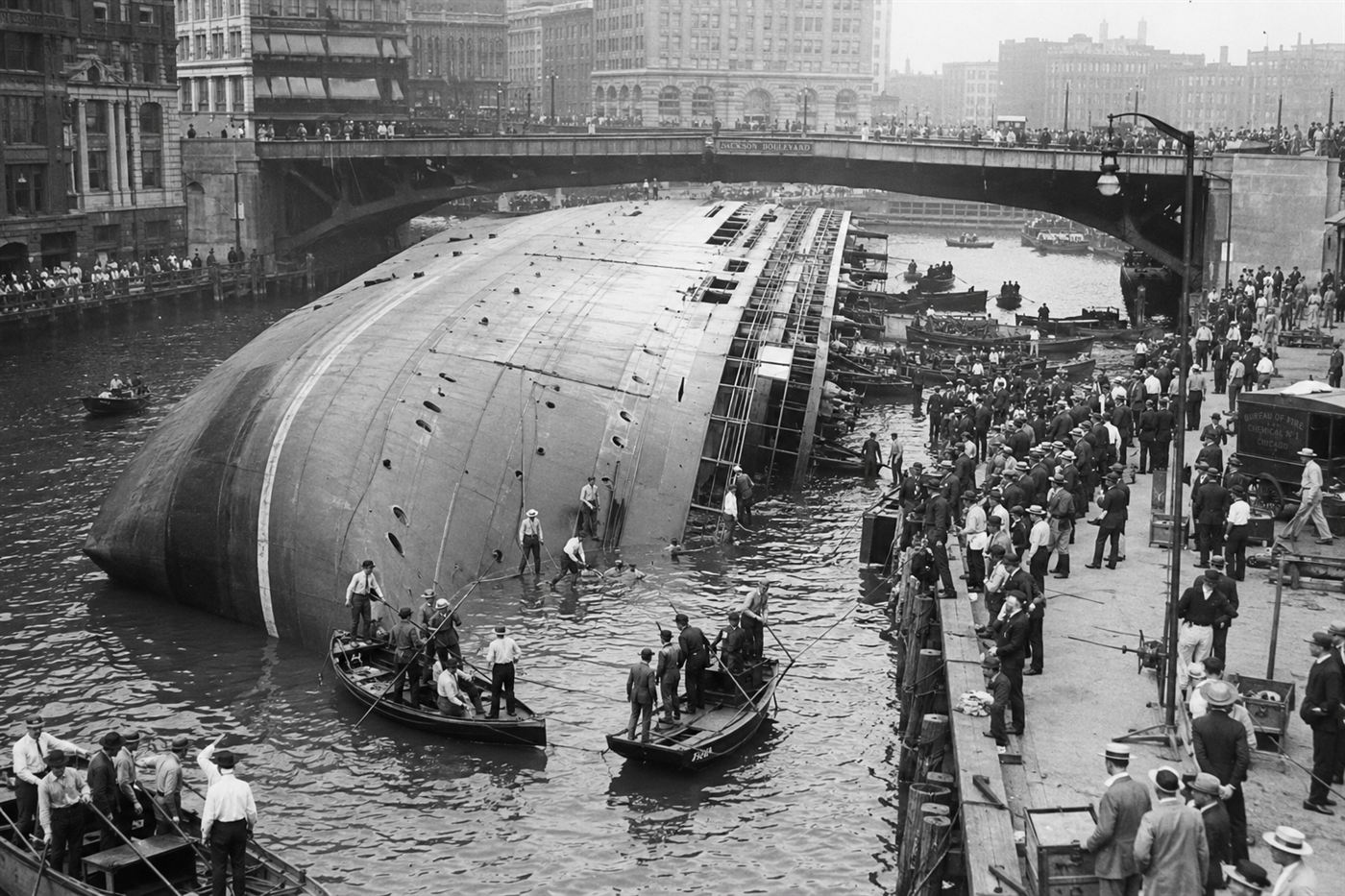 SS Eastland disaster 1915 Chicago River, steamship capsized on its side at the dock with rescuers alongside the overturned hull