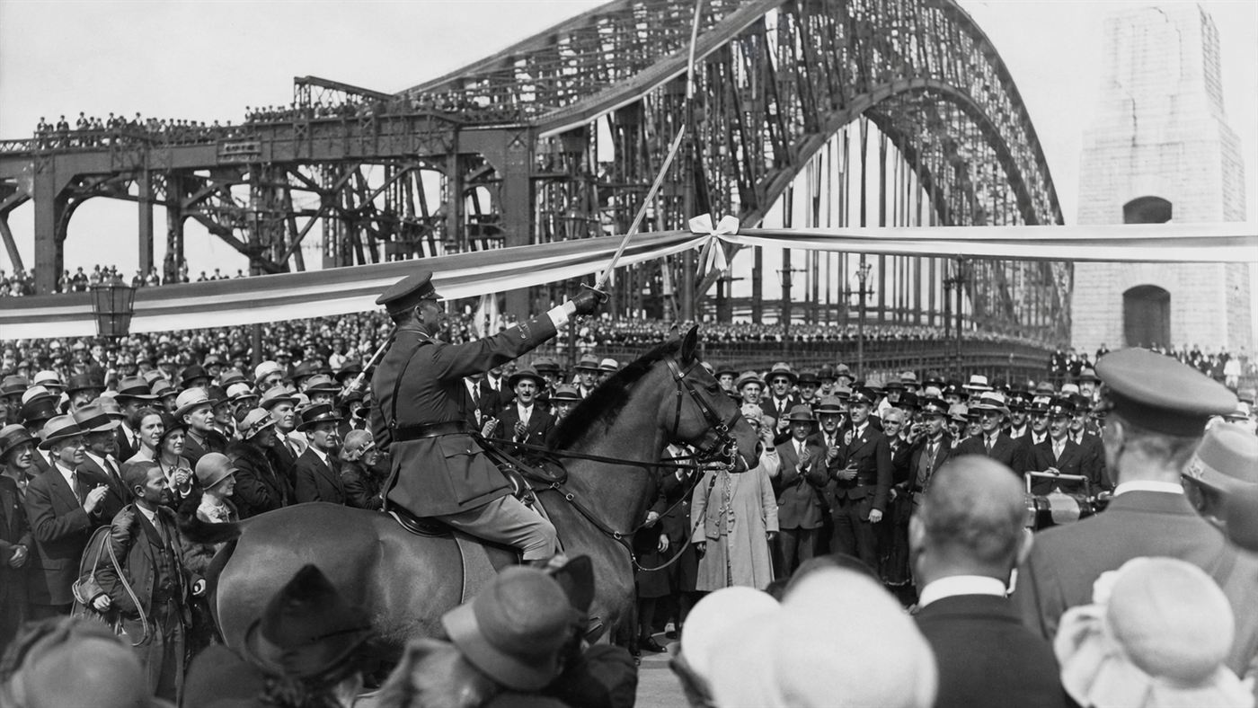 A man in uniform on horseback raising a sword at the ribbon during the Sydney Harbour Bridge opening in 1932
